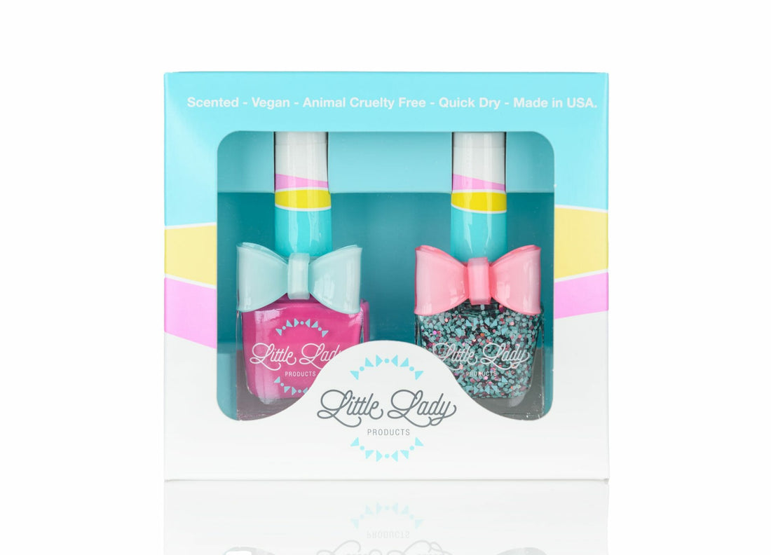 Flamingo Dino Duo: Box of kid-friendly nail polishes from Little Lady Products, featuring a pink bottle and glitter bottle, each adorned with a bow.